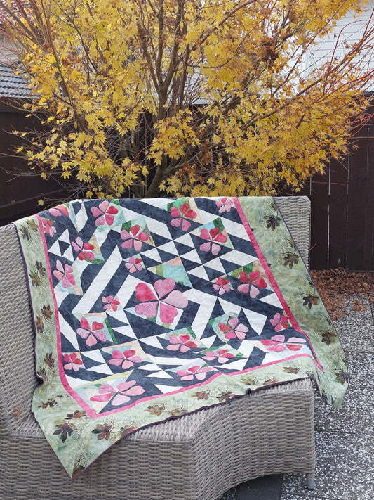 Ginkgo Garden quilt pattern displayed on outdoor furniture in front of turning maple tree