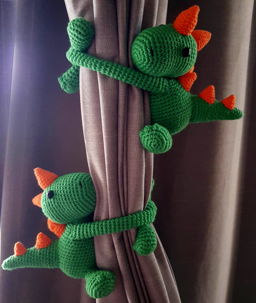 pair of green dino tie backs with orange spikes