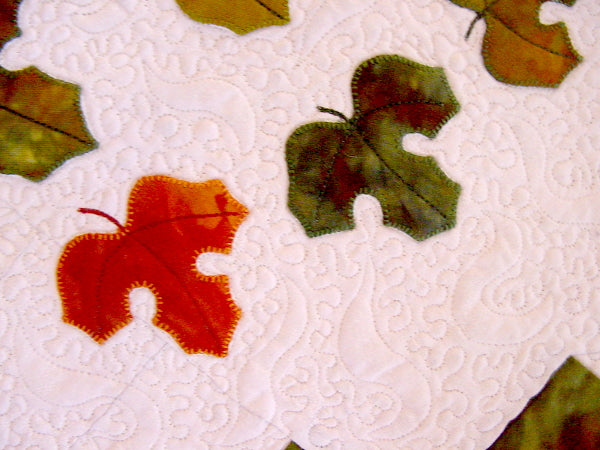 Close up of applique fall leaves and quilting design in Autumn Swirls quilt pattern