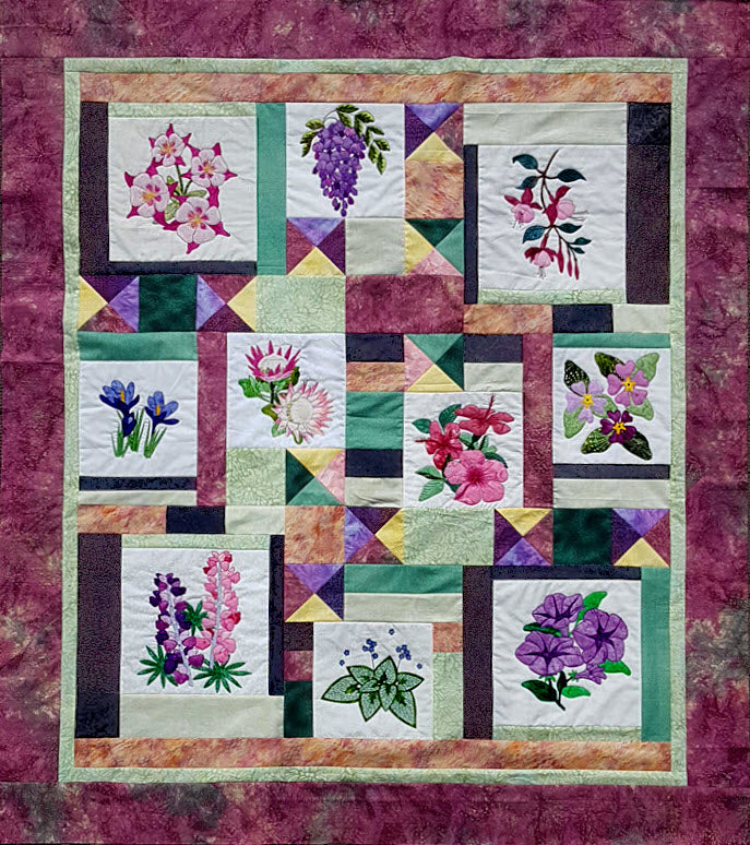 patchwork quilt decorated with flower applique blocks. Quilt pattern available
