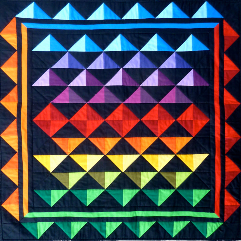 a patchwork quilt of triangle in color gradiation. This quilt pattern is designed by Anita Eaton