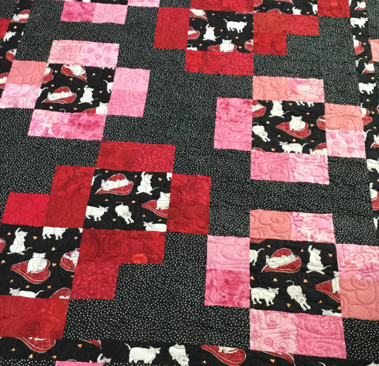 Stepping stones quilt pattern made by Sue Salinger and designed by Ruth Blanchet. It uses a theme fabric of cats which is enhanced with pink red and black - closeup of quilt