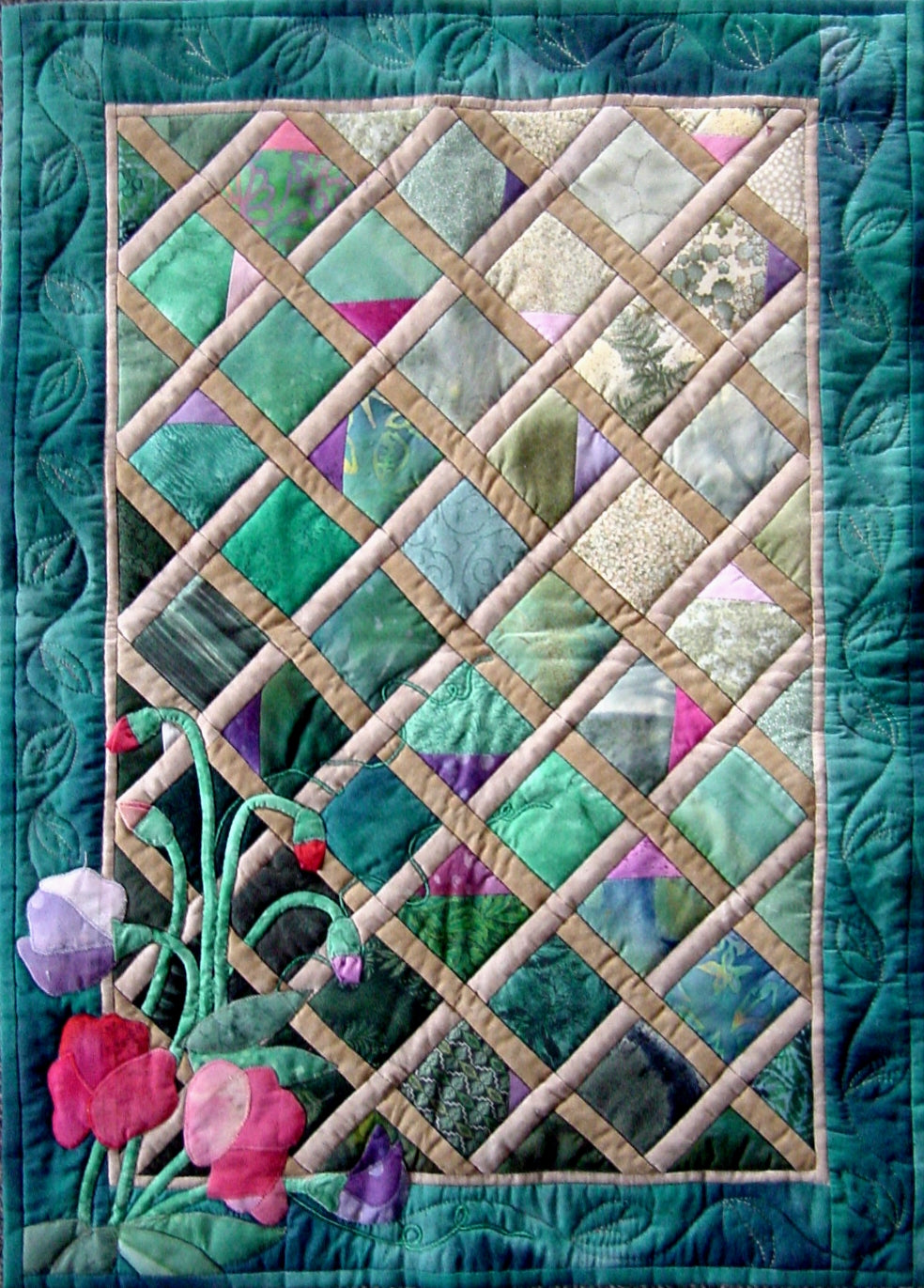 A small quilt wall hanging with sweet pea flowers and buds in the corner of a trellis