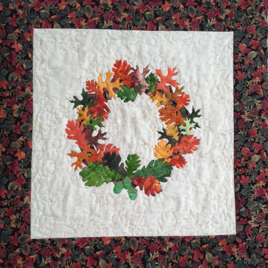 this thanksgiving quilt design has a wreath of leaves in the center and the background is quilted down with leaf designs
